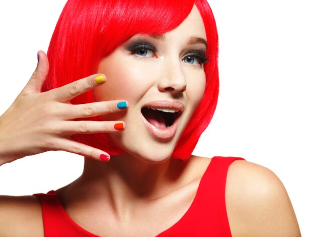 밝은 빨간 머리카락과 여러 가지 빛깔의 손톱을 가진 젊은 예쁜 여자의 놀란 얼굴.