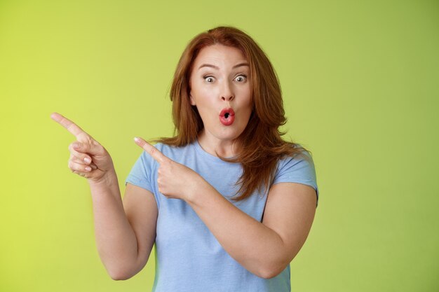 Surprised fascinated enthusiastic redhead middleaged woman impressed