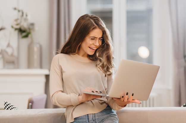 Surprised female student in glasses looking at computer screen