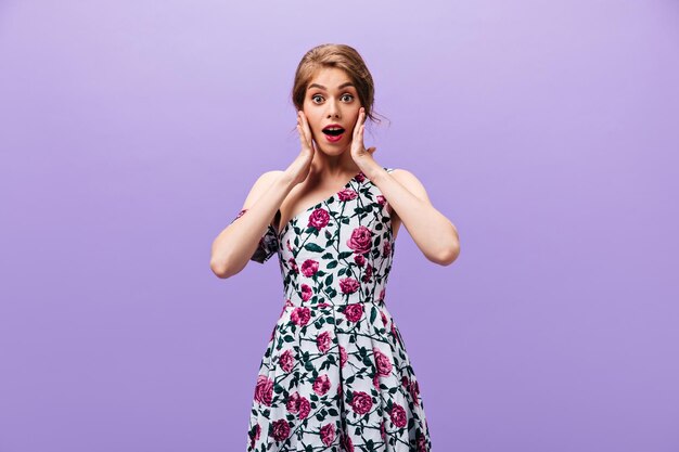 Surprised girl in gorgeous dress looks into camera Beautiful fashionable woman in floral bright clothes posing on isolated background