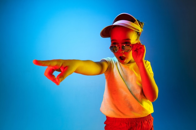 Surprised girl pointing isolated on blue wall