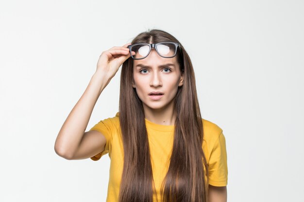 Surprised girl taking off her glasses isolated on white wall