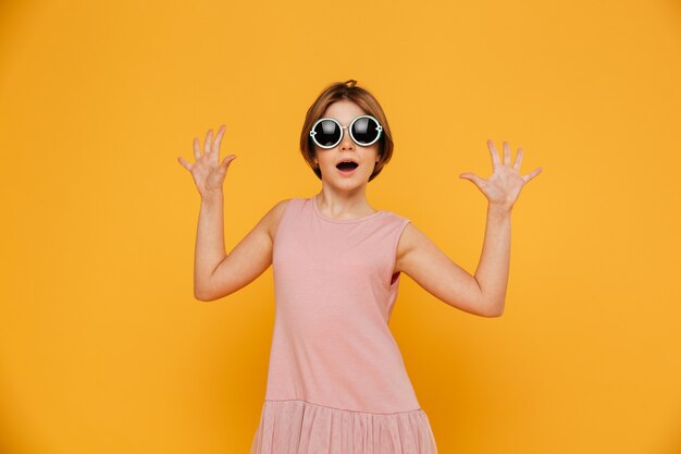 Surprised girl with raised hands looking camera