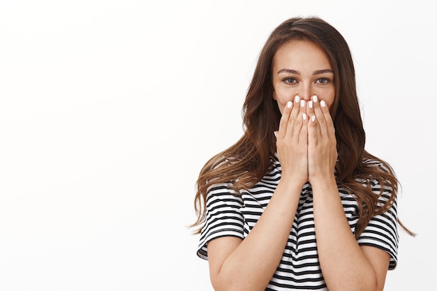 Free photo surprised glad cute young woman in striped t-shirt ambushed with unexpected awesome b-day surprise, cover mouth gasping impressed, look camera speechless and happy, white wall