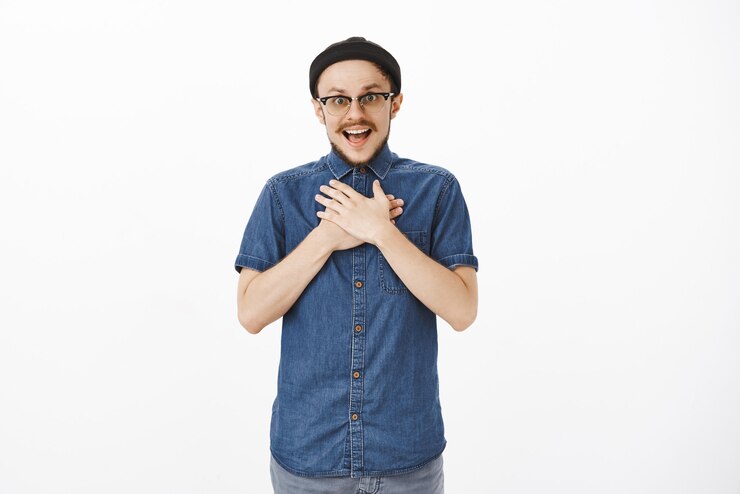 Free Photo surprised and grateful handsome male coworker being congratulated with b-day by team holding hands on breast and gasping from amazement and delight thanking over white wall