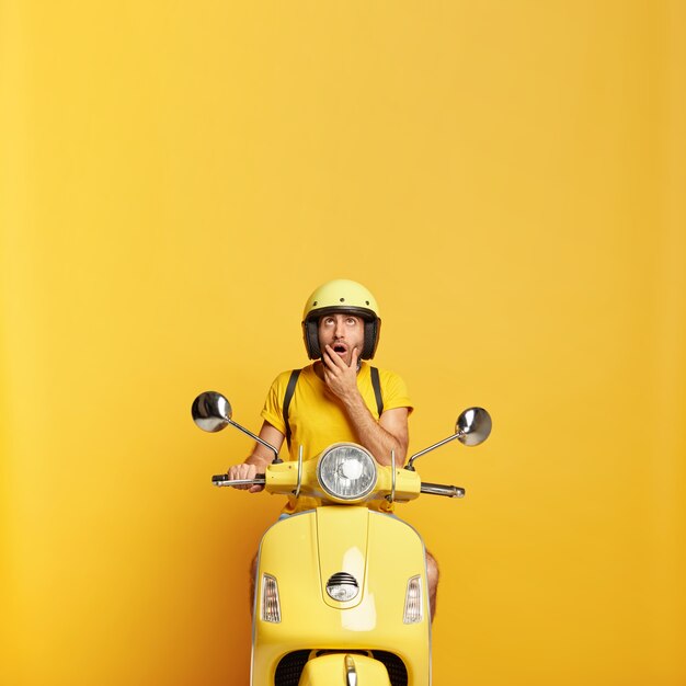 surprised guy with helmet driving yellow scooter