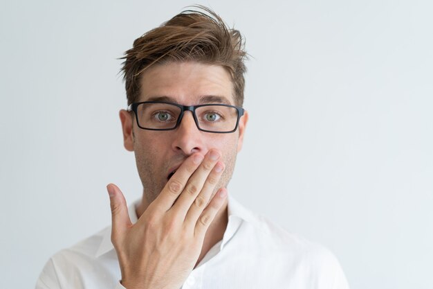 Surprised handsome man covering mouth with hand