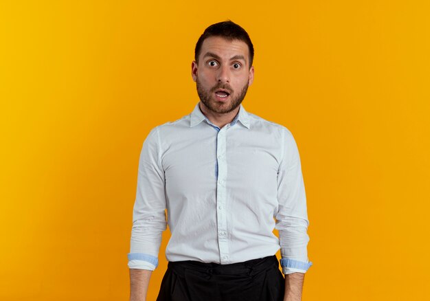 Surprised handsome man looks isolated on orange wall