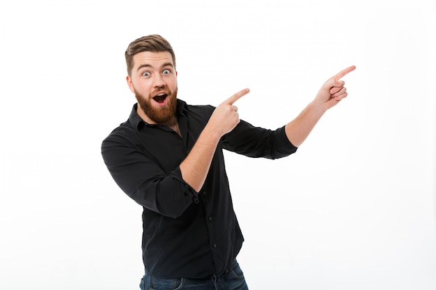 Surprised happy bearded man in shirt pointing away