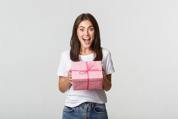 Surprised happy birthday girl receiving wrapped gift, white.