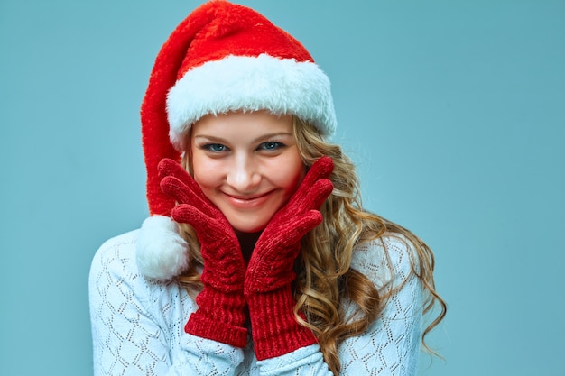 산타 모자를 입은 놀라고 행복한 소녀. 파란색으로 휴일 개념입니다.