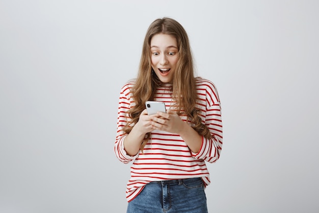 Surprised happy girl reading awesome news smartphone screen