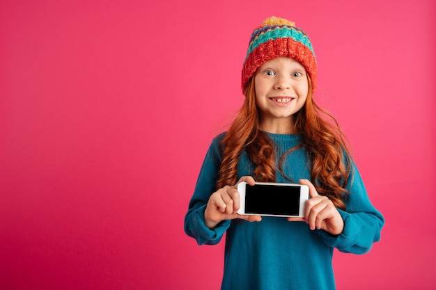 Free photo surprised happy girl showing smartphone with blank screen and smiling isolated