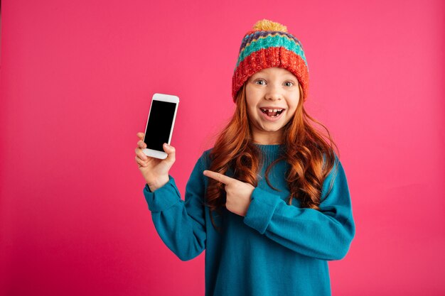 Surprised happy girl showing smartphone with blank screen and smiling isolated