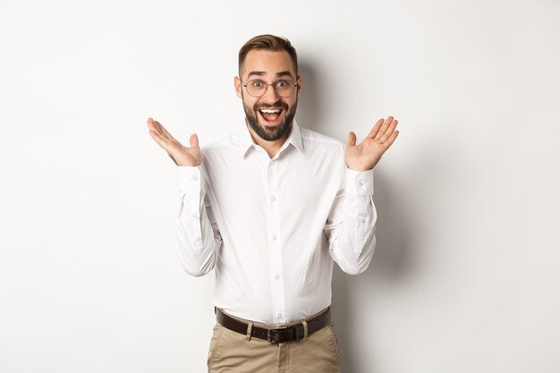 Surprised happy male entrepreneur clap hands and smiling, looking amazed at camera, standing over