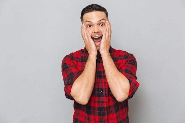 Surprised happy man holding his cheeks