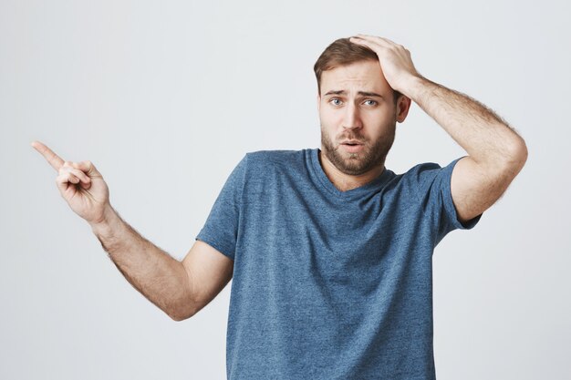 Surprised happy man pointing finger left at banner