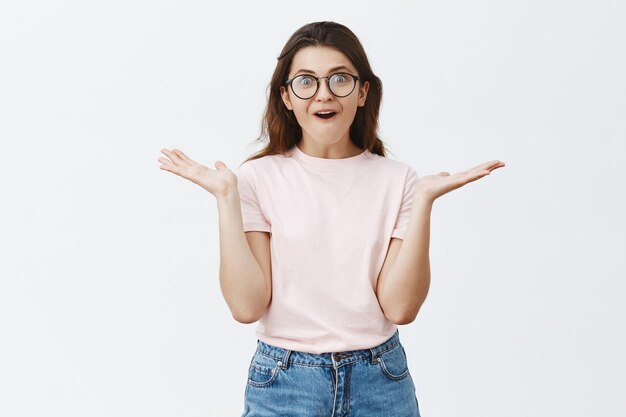 Surprised happy young brunette with glasses posing