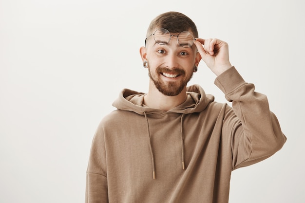 Free photo surprised hipster guy with beard, smiling happy and take-off glasses