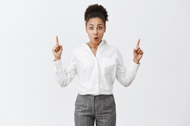 Surprised and impressed african-american girl gasping amazed, pointing fingers up