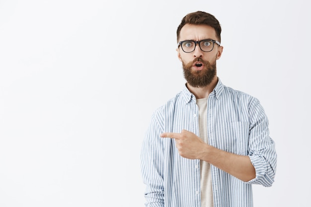 Free photo surprised and impressed bearded man posing against the white wall