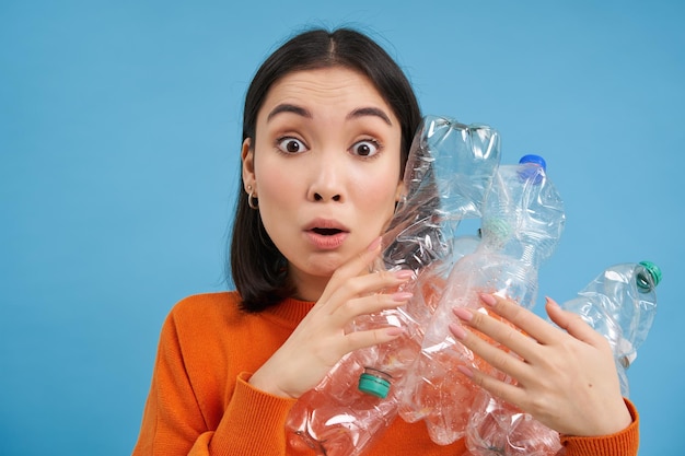 Free photo surprised korean woman holding plastic bottles looking shocked at camera concept of environment and