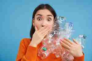 Free photo surprised korean woman holding plastic bottles looking shocked at camera concept of environment and