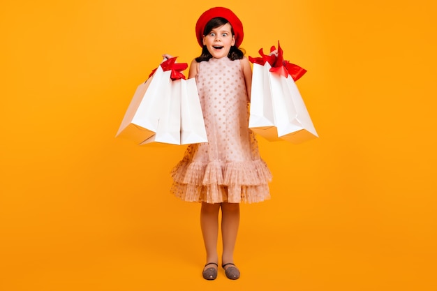 Surprised little girl in french beret posing after shopping.  amazed kid with paper bags.