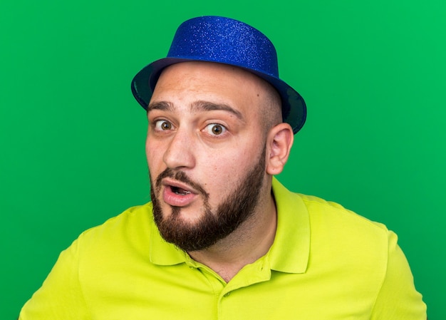 Surprised looking at camera young man wearing blue party hat 