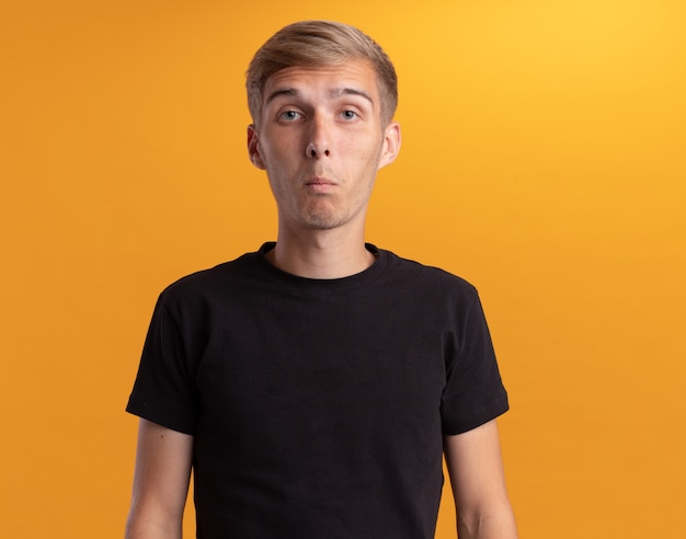 Free photo surprised looking at front young handsome guy wearing black shirt isolated on yellow wall