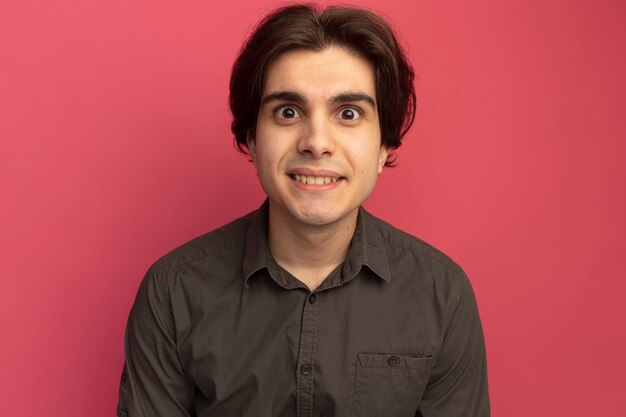 Surprised looking at front young handsome guy wearing black t-shirt isolated on pink wall