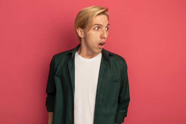 Surprised looking at side young blonde guy wearing green t-shirt