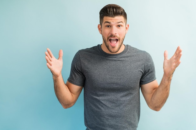 Foto gratuita maschio sorpreso che gesturing stando in piedi con la bocca aperta in studio