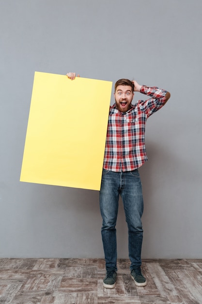 Free photo surprised man holding blank board