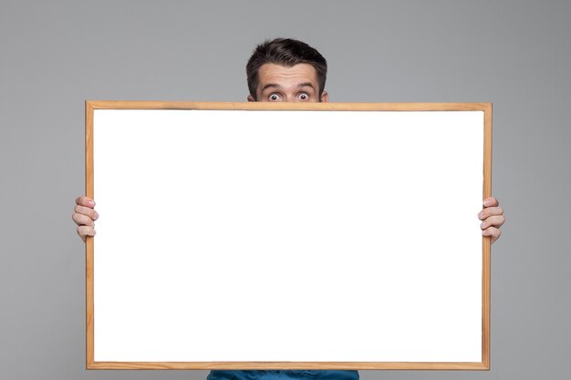 Surprised man showing empty white board