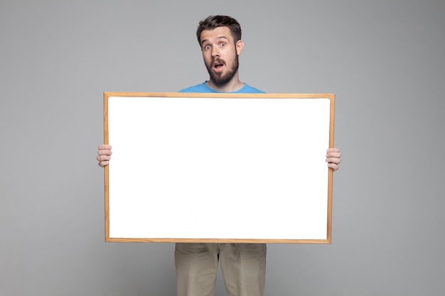 Surprised man showing empty white board