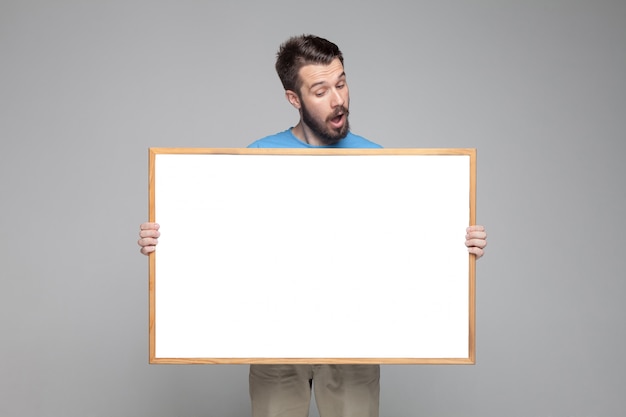 Surprised man showing empty white board