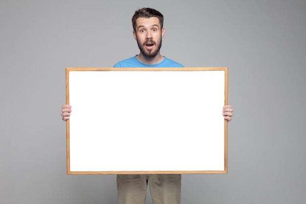 Free photo surprised man showing empty white board