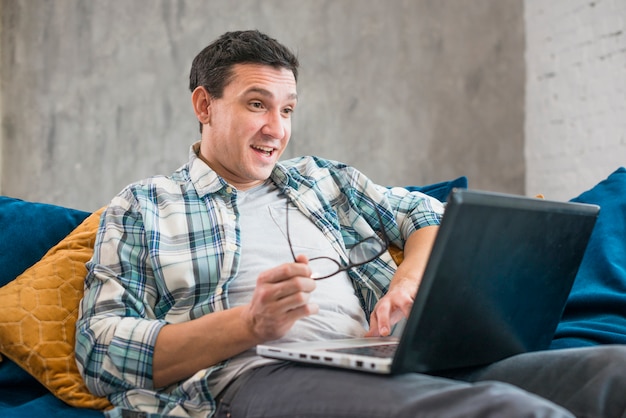 Surprised man using laptop on sofa 