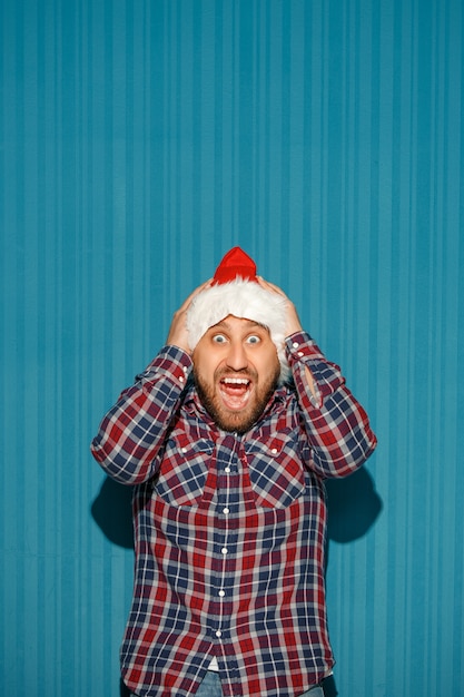 surprised man wearing a santa hat on blue background