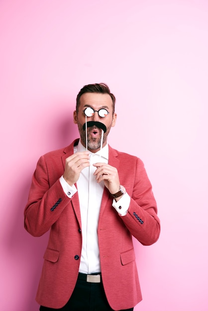 Free photo surprised man with paper moustache and eyeglasses making faces