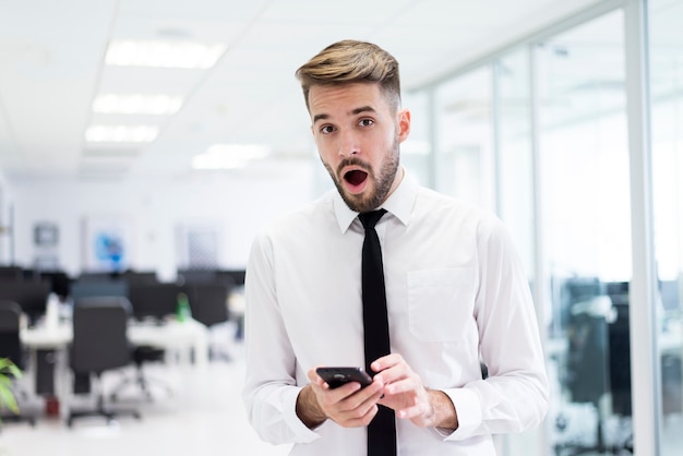 Foto gratuita sorpreso l'uomo con un telefono in mano