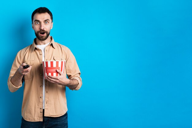 Surprised man with  popcorn bucket and remote control