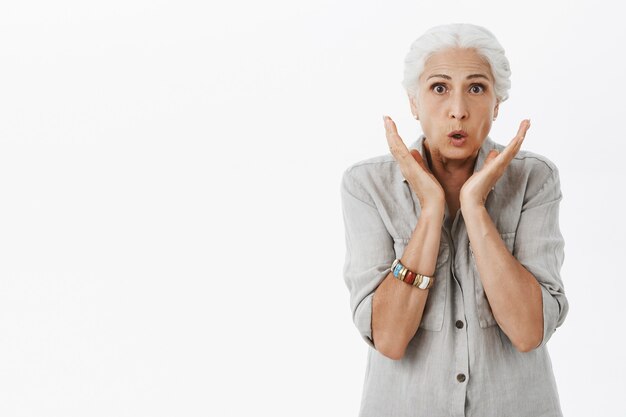 Surprised mature woman with grey hair looking amazed, react to awesome news