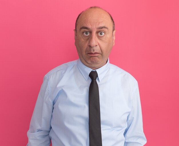 Surprised  middle-aged man wearing white t-shirt with tie isolated on pink wall