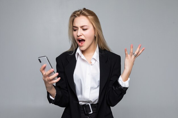 Surprised pretty businesswoman chatting by phone standing isolated.