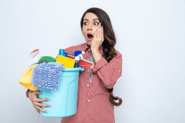 Surprised pretty caucasian cleaner woman holding cleaning equipment and looking at side 