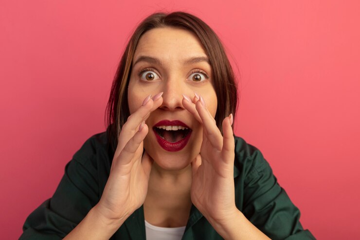 Free Photo surprised pretty caucasian woman holds hands close to mouth looking at camera on pink