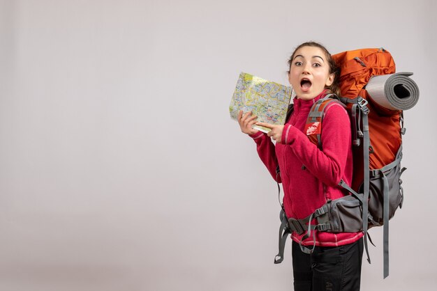 surprised pretty woman with big backpack holding map