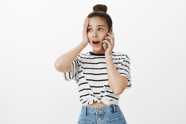 Surprised and relieved attractive girl receive good news over phone call, talking on smartphone